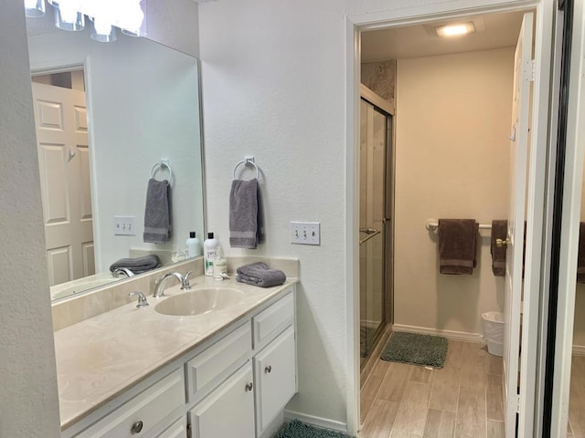 bathroom with hardwood / wood-style floors, vanity, and a shower with door