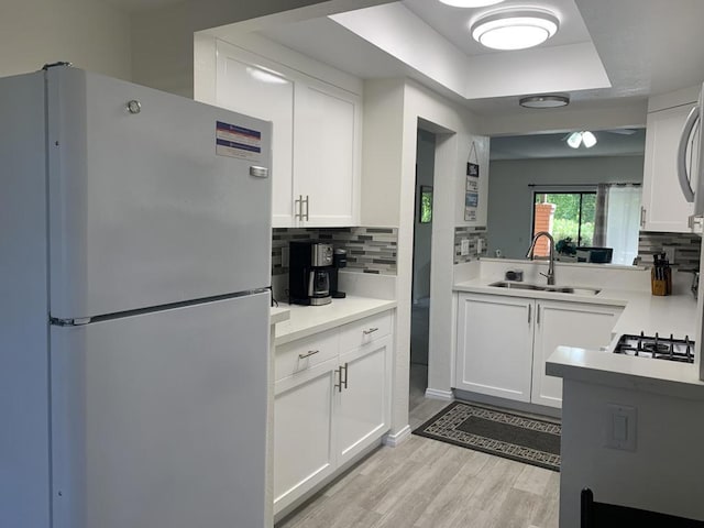 kitchen featuring sink, white cabinets, fridge, and light hardwood / wood-style flooring