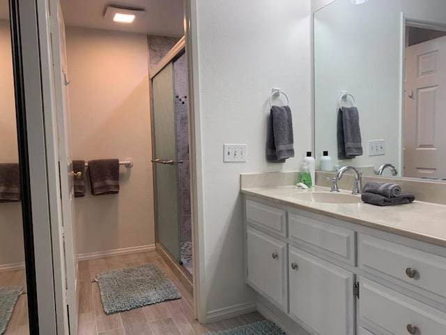 bathroom with hardwood / wood-style floors, vanity, and an enclosed shower