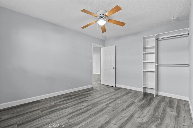 unfurnished bedroom featuring ceiling fan, a closet, wood-type flooring, and a textured ceiling