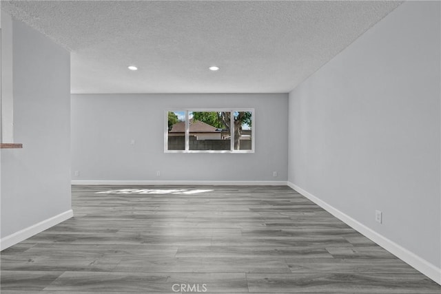 spare room featuring a textured ceiling and light hardwood / wood-style flooring