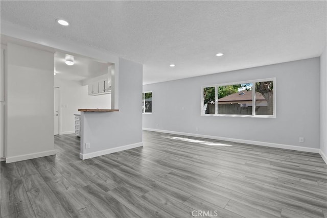 unfurnished living room with a textured ceiling and light wood-type flooring