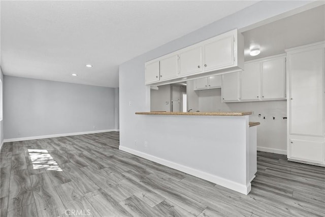 kitchen featuring kitchen peninsula, white cabinetry, and light hardwood / wood-style flooring