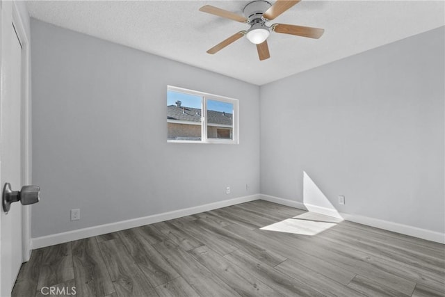 spare room featuring ceiling fan, wood-type flooring, and a textured ceiling