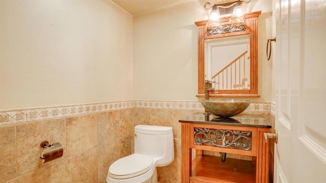 bathroom featuring vanity, toilet, and tile walls