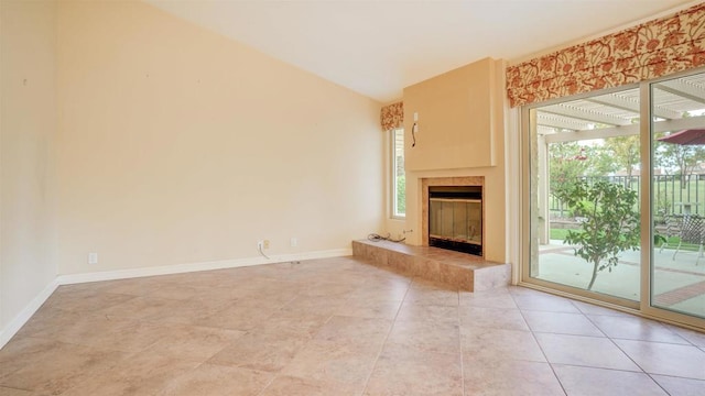 unfurnished living room with a tiled fireplace, tile patterned floors, and lofted ceiling