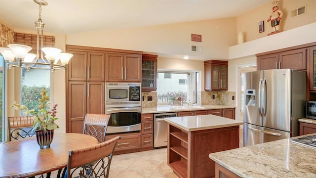 kitchen with lofted ceiling, a center island, a notable chandelier, pendant lighting, and appliances with stainless steel finishes