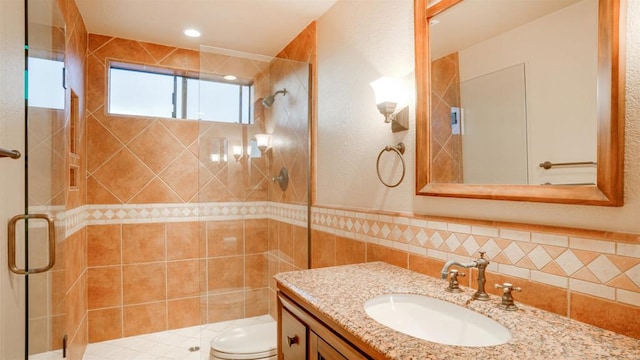 bathroom featuring vanity, toilet, tile walls, and a shower with shower door