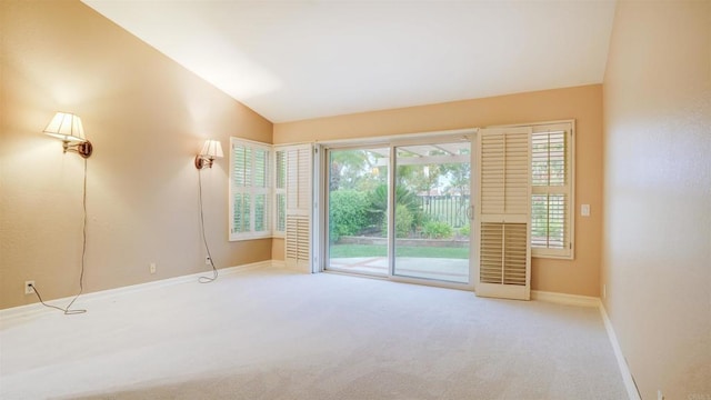 empty room featuring light carpet, vaulted ceiling, and a wealth of natural light