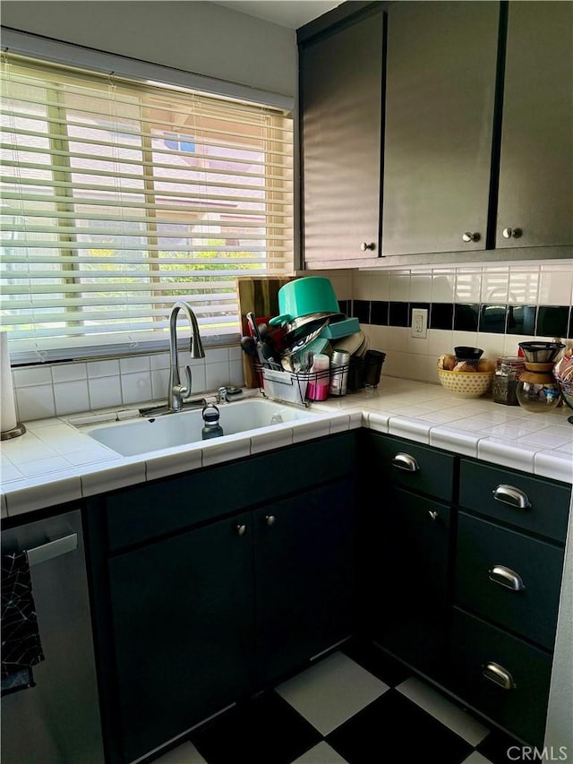 kitchen featuring backsplash, tile counters, sink, and dishwasher