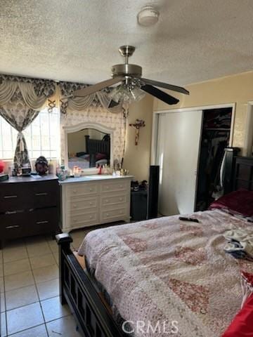 tiled bedroom featuring ceiling fan, a textured ceiling, and a closet