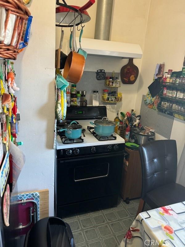 kitchen with white gas stove and range hood