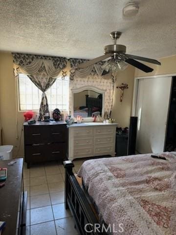 tiled bedroom with ceiling fan and a textured ceiling