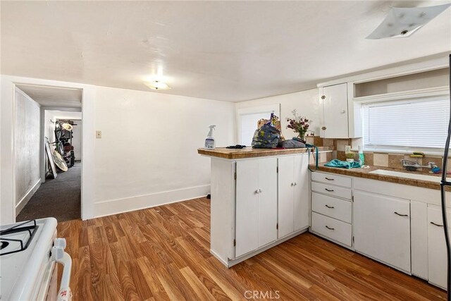 kitchen with light hardwood / wood-style floors, sink, white cabinetry, and white gas range oven