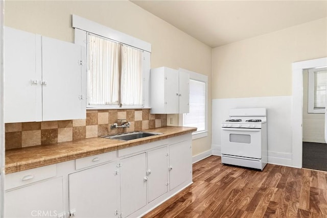 kitchen featuring tasteful backsplash, white range oven, sink, white cabinets, and hardwood / wood-style floors