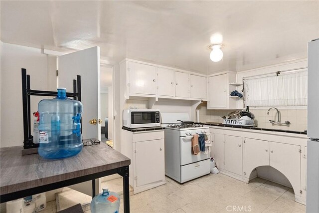 kitchen featuring white cabinets, sink, white appliances, and backsplash