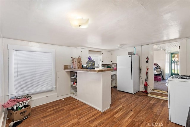 kitchen with kitchen peninsula, white cabinetry, dark wood-type flooring, and white appliances