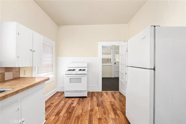 kitchen featuring white cabinets, light hardwood / wood-style floors, white appliances, and tasteful backsplash