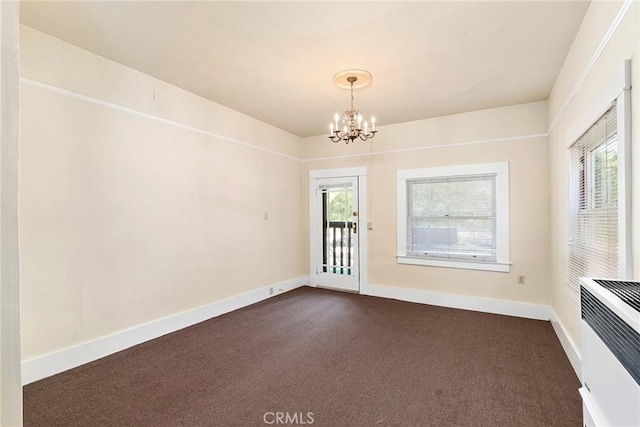 carpeted spare room with heating unit and an inviting chandelier