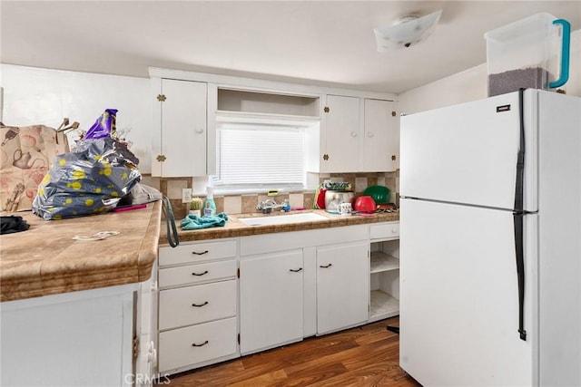 kitchen featuring tasteful backsplash, dark wood-type flooring, sink, white fridge, and white cabinetry