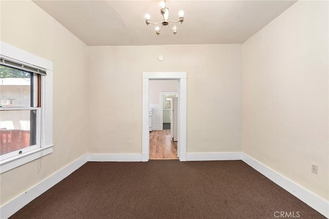 carpeted empty room with a chandelier