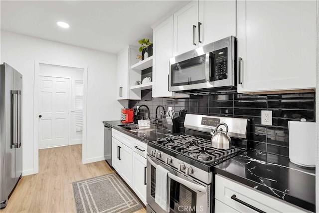 kitchen featuring tasteful backsplash, sink, white cabinetry, light wood-type flooring, and appliances with stainless steel finishes