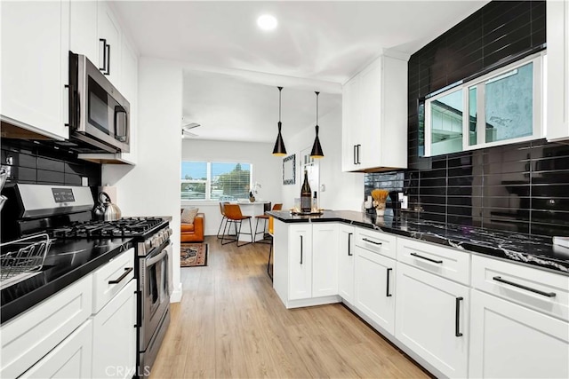 kitchen with white cabinets, decorative light fixtures, stainless steel appliances, tasteful backsplash, and light wood-type flooring