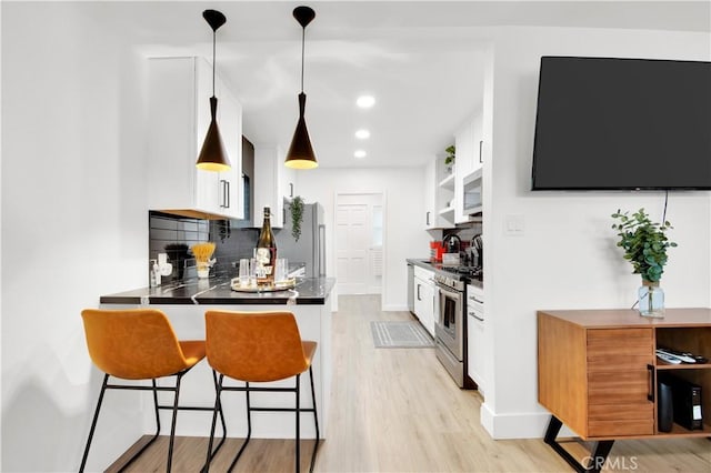 kitchen featuring kitchen peninsula, appliances with stainless steel finishes, decorative backsplash, pendant lighting, and white cabinets