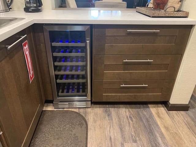 interior space with dark brown cabinetry, wood-type flooring, and beverage cooler