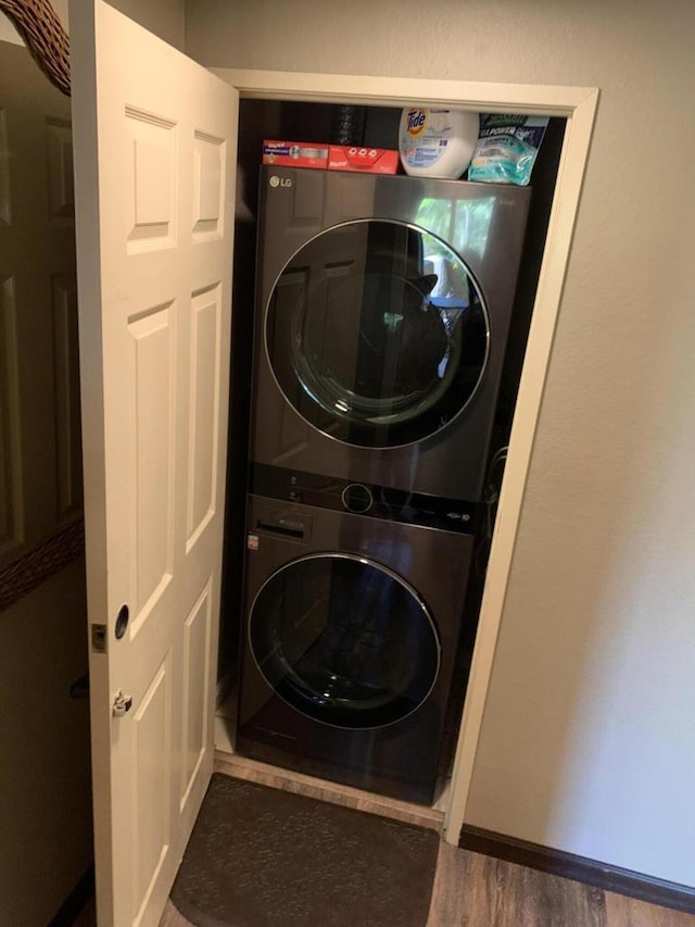 laundry area featuring dark hardwood / wood-style floors and stacked washer / dryer