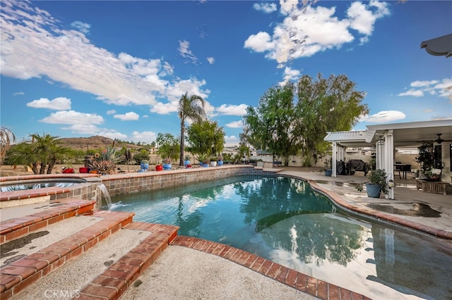 view of pool with an in ground hot tub, a mountain view, pool water feature, and a patio area