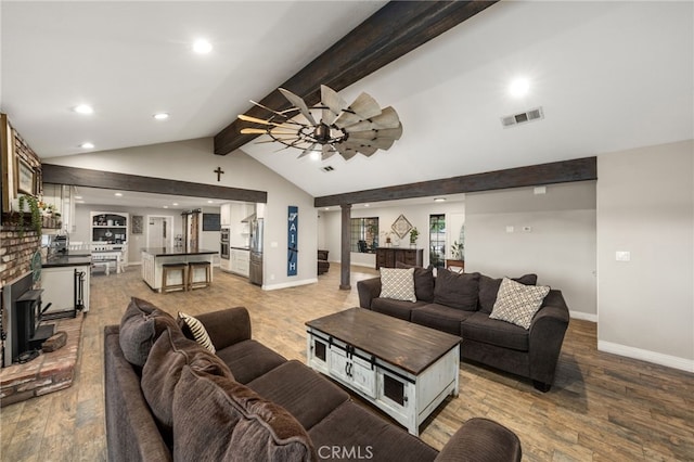 living room with hardwood / wood-style flooring, vaulted ceiling with beams, and ceiling fan