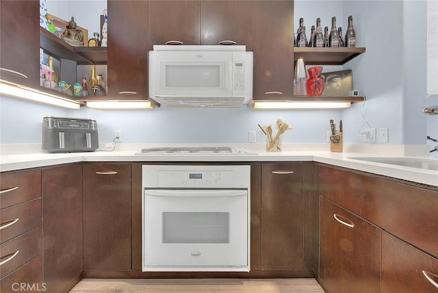 kitchen featuring white appliances, light countertops, dark brown cabinets, and open shelves