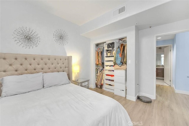 bedroom with light wood finished floors, baseboards, visible vents, and a closet