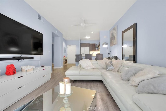 living area featuring visible vents, light wood-type flooring, and a ceiling fan