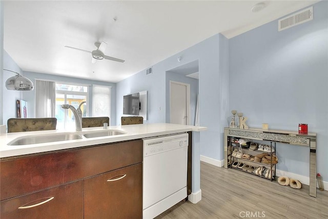 kitchen featuring light wood-type flooring, visible vents, white dishwasher, and a sink