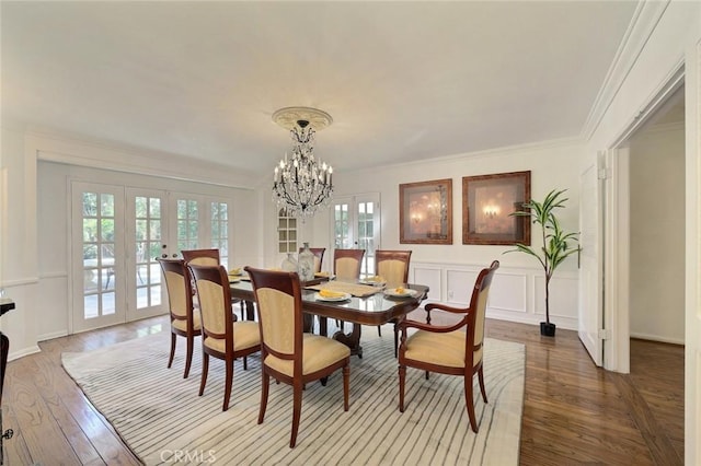 dining room with a notable chandelier, light hardwood / wood-style floors, ornamental molding, and french doors