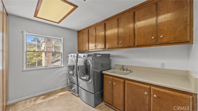 laundry area featuring cabinets, washer and clothes dryer, and sink