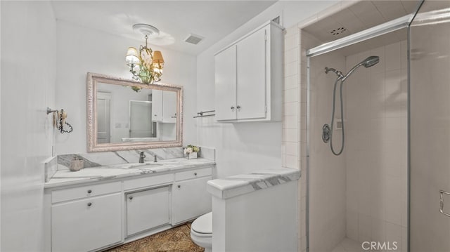 bathroom featuring a notable chandelier, toilet, a shower with shower door, and vanity