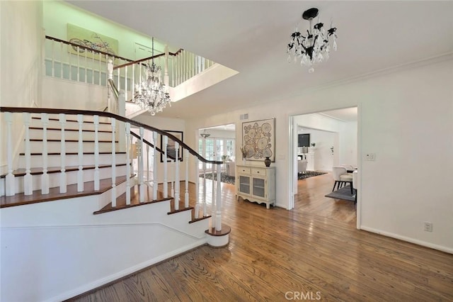 stairway with hardwood / wood-style floors and an inviting chandelier