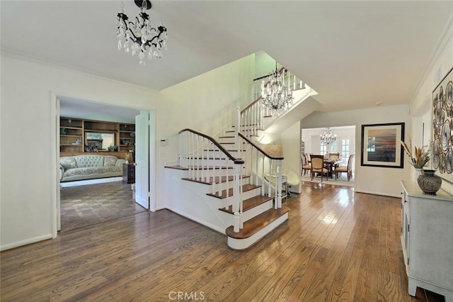 stairway with hardwood / wood-style flooring, a notable chandelier, ornamental molding, and built in shelves