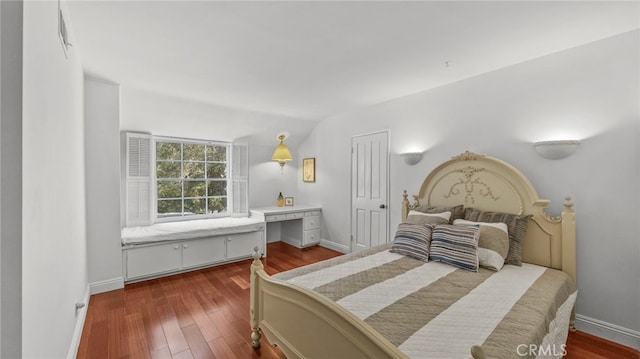 bedroom with dark hardwood / wood-style flooring, vaulted ceiling, and built in desk