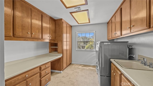 clothes washing area with cabinets, washer / clothes dryer, and sink