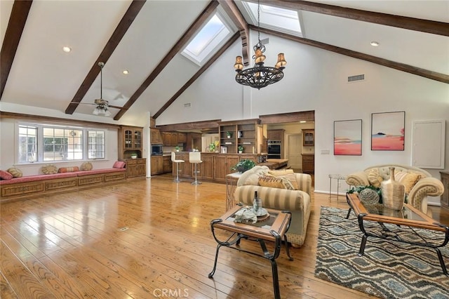 living room with high vaulted ceiling, ceiling fan with notable chandelier, and light wood-type flooring