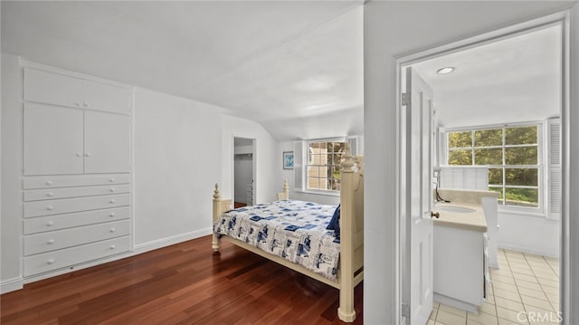 bedroom featuring connected bathroom, multiple windows, and hardwood / wood-style floors