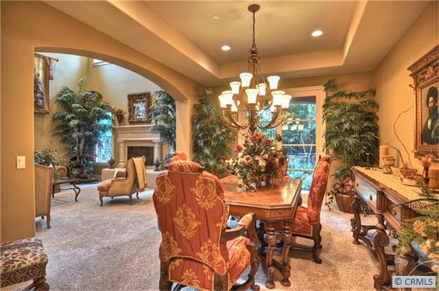 carpeted dining room with a raised ceiling and a notable chandelier