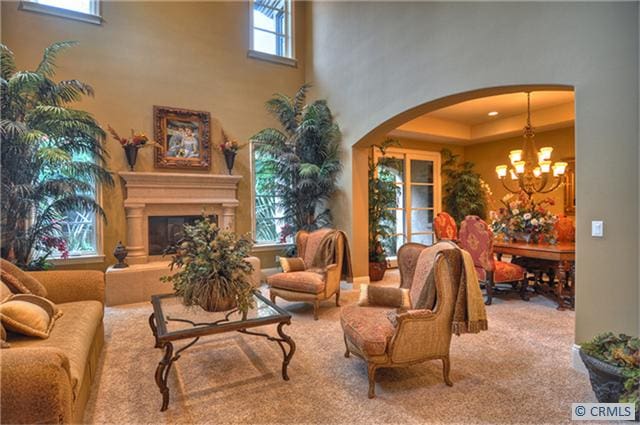 carpeted living room with a high ceiling and an inviting chandelier