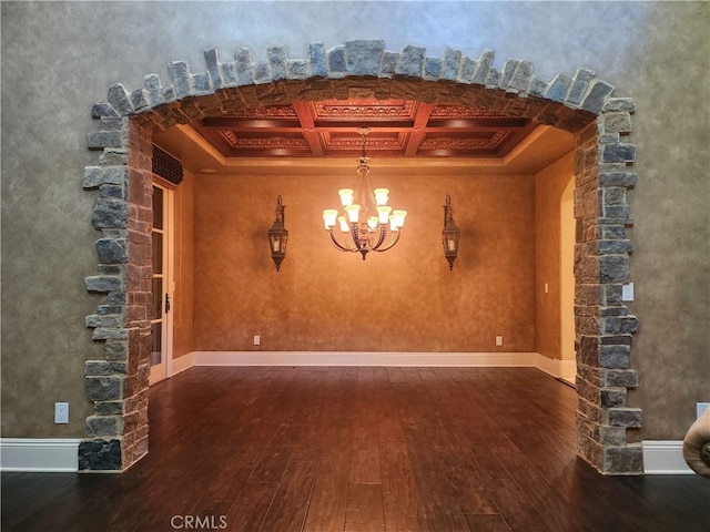 unfurnished dining area with beamed ceiling, dark hardwood / wood-style floors, an inviting chandelier, and coffered ceiling