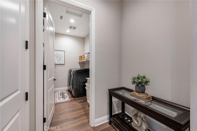 laundry area with independent washer and dryer and wood-type flooring