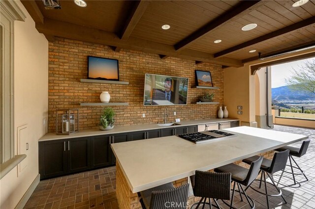 kitchen with beamed ceiling, sink, stainless steel gas stovetop, a kitchen island, and a mountain view